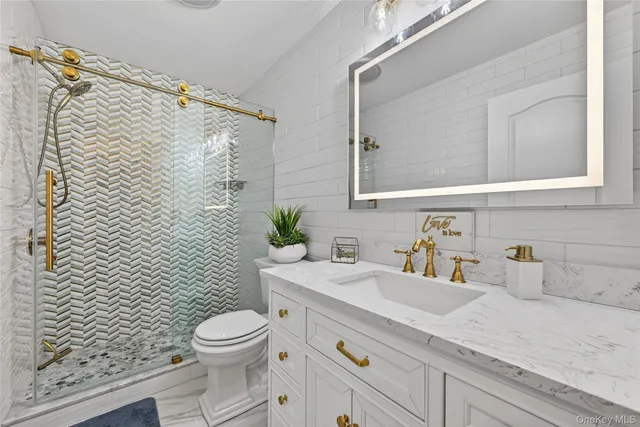 a bathroom with a granite countertop toilet a sink and a mirror