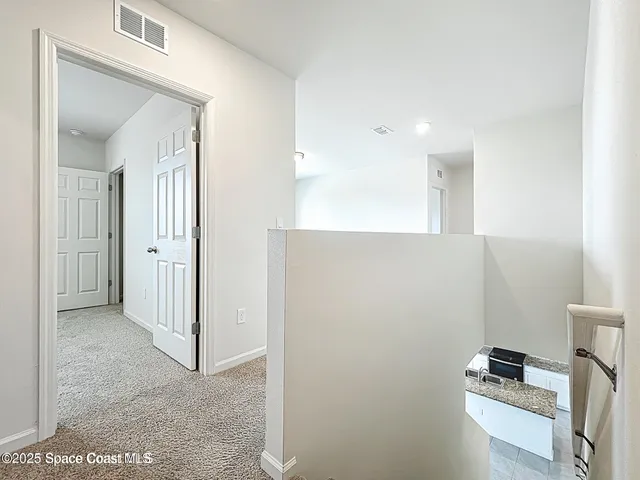 a view of kitchen with hallway and white cabinets