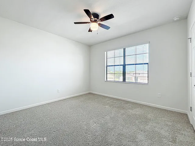 an empty room with ceiling fan and windows