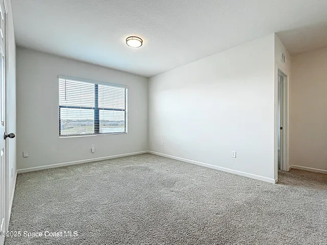 an empty room with windows & cabinet
