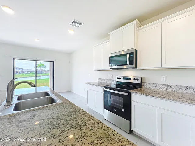 a kitchen with stainless steel appliances granite countertop a stove a sink and a microwave