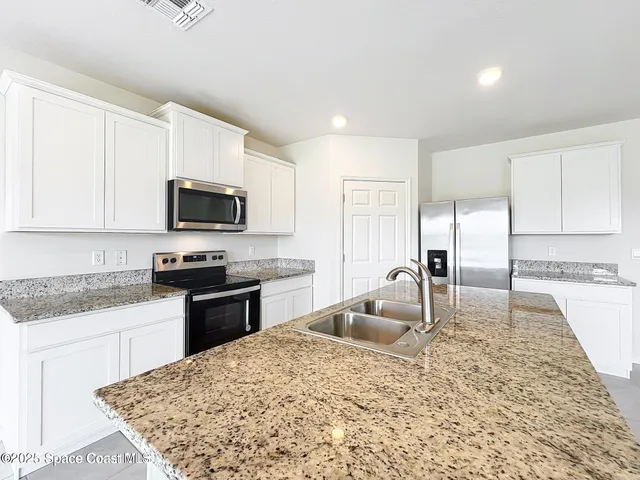 a kitchen with granite countertop a sink a stove top oven and appliances