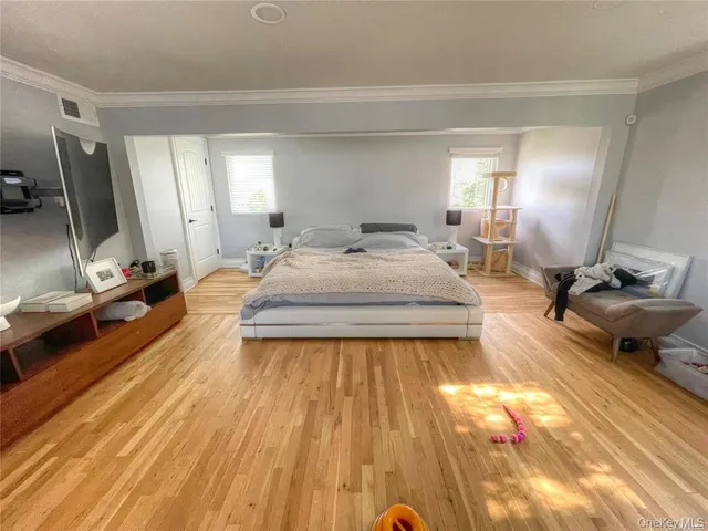 a spacious bedroom with a bed a rug and wooden floor