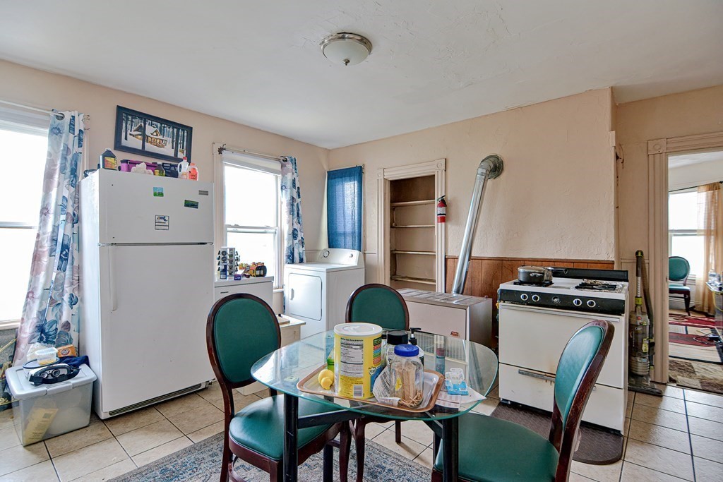 83 Ward Street Worcester, MA 01610 - Photo 17 of 28 a kitchen with a refrigerator a stove a dining table and chairs