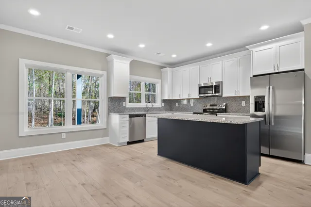 a kitchen with stainless steel appliances granite countertop a refrigerator a sink a stove a microwave and white cabinets