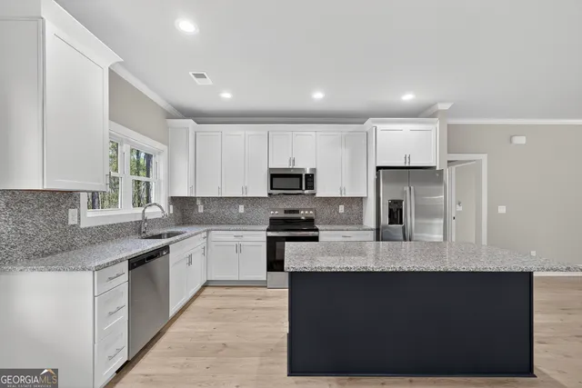 a large kitchen with granite countertop lots of counter top space and stainless steel appliances