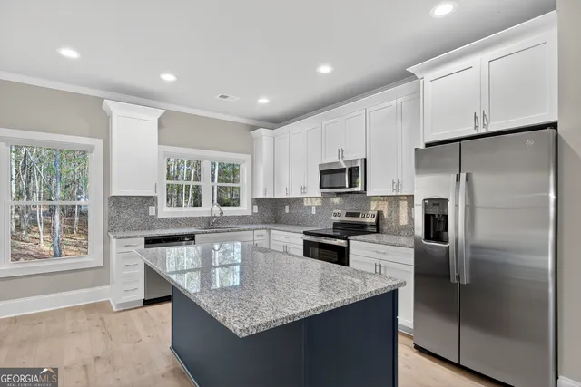 a kitchen with granite countertop kitchen island stainless steel appliances a refrigerator a stove a sink a center island and a window