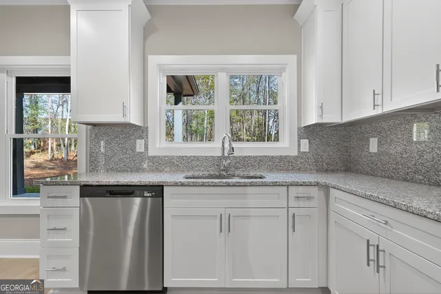 a kitchen with granite countertop white cabinets and a window