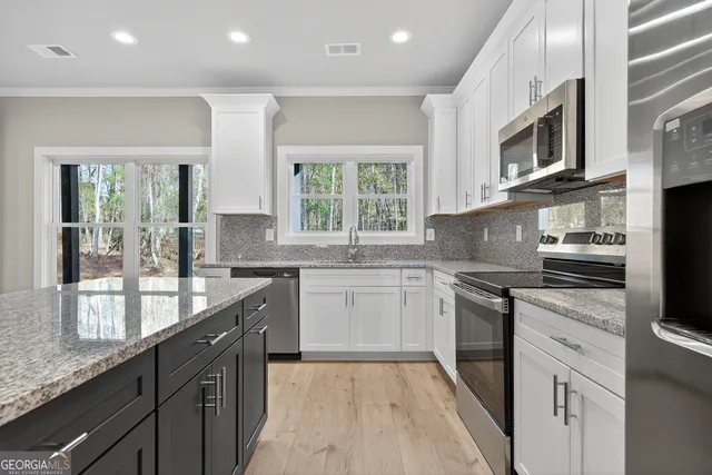 a kitchen with stainless steel appliances granite countertop a stove a sink and a microwave