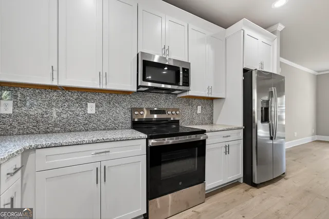 a kitchen with stainless steel appliances granite countertop white cabinets stove and microwave
