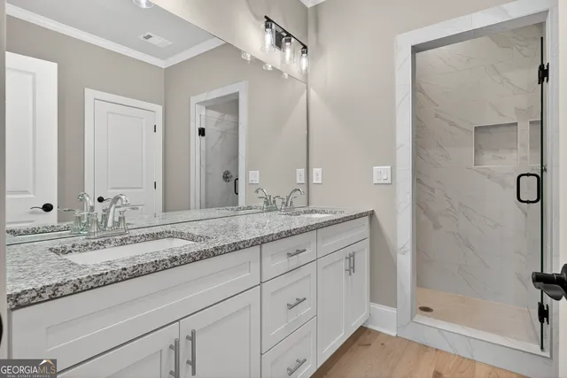 a bathroom with a granite countertop sink two mirror and shower
