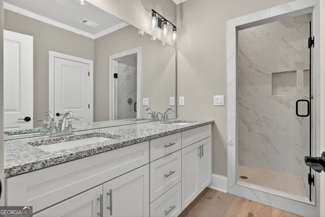 a bathroom with a granite countertop sink two mirror and shower