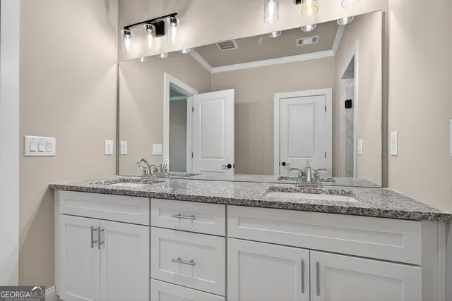a bathroom with a granite countertop double vanity sink and mirror