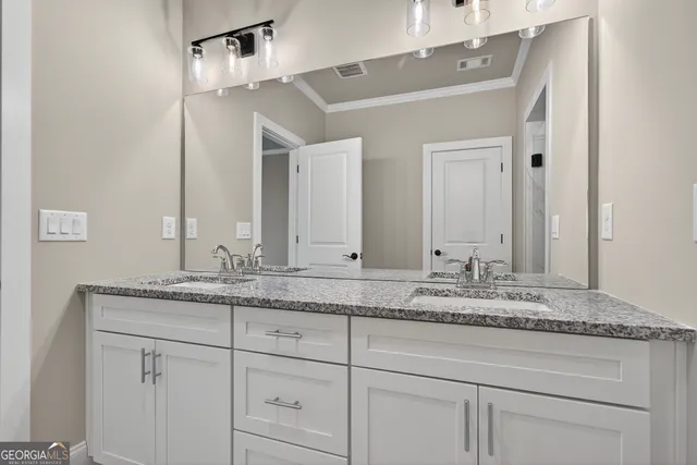 a bathroom with a granite countertop double vanity sink and mirror