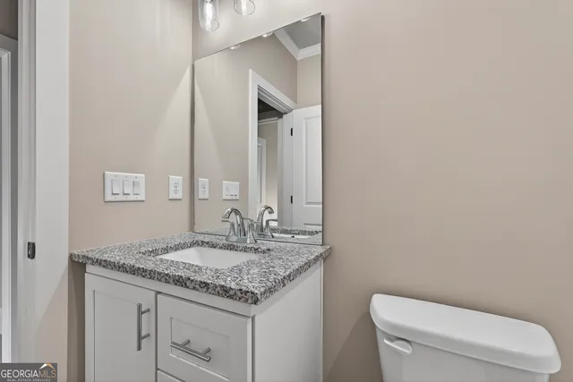 a bathroom with a granite countertop toilet sink and mirror