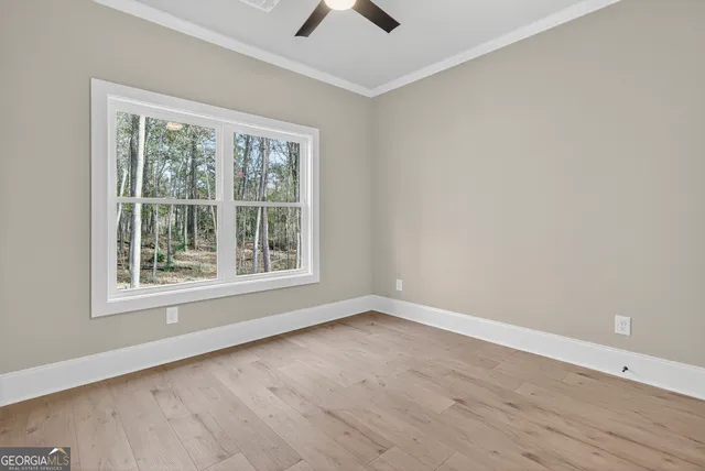 a view of an empty room with window and wooden floor