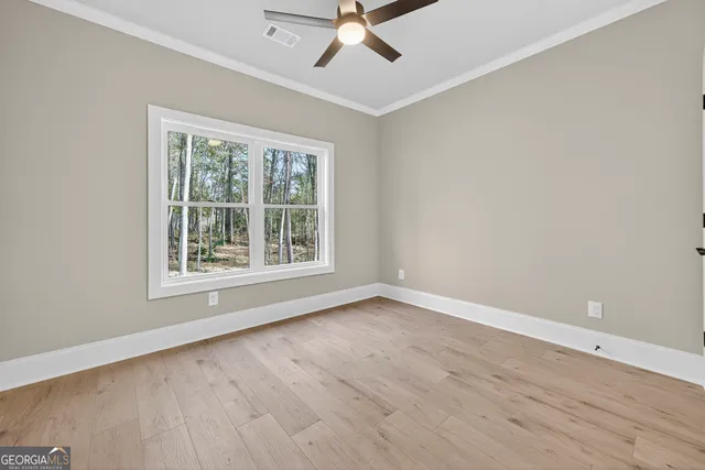 an empty room with wooden floor chandelier fan and windows
