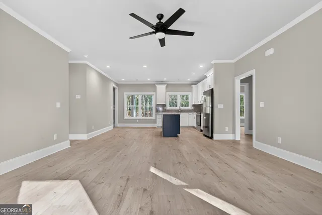a view of a livingroom with a stove wooden cabinets and a ceiling fan