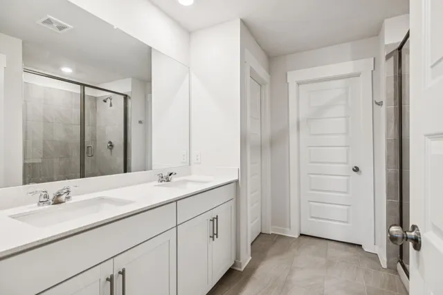 a en suite bathroom with a double vanity sink and a mirror