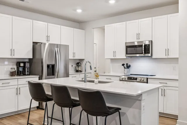 a kitchen with stainless steel appliances a sink a stove a refrigerator cabinets and a refrigerator with wooden floor