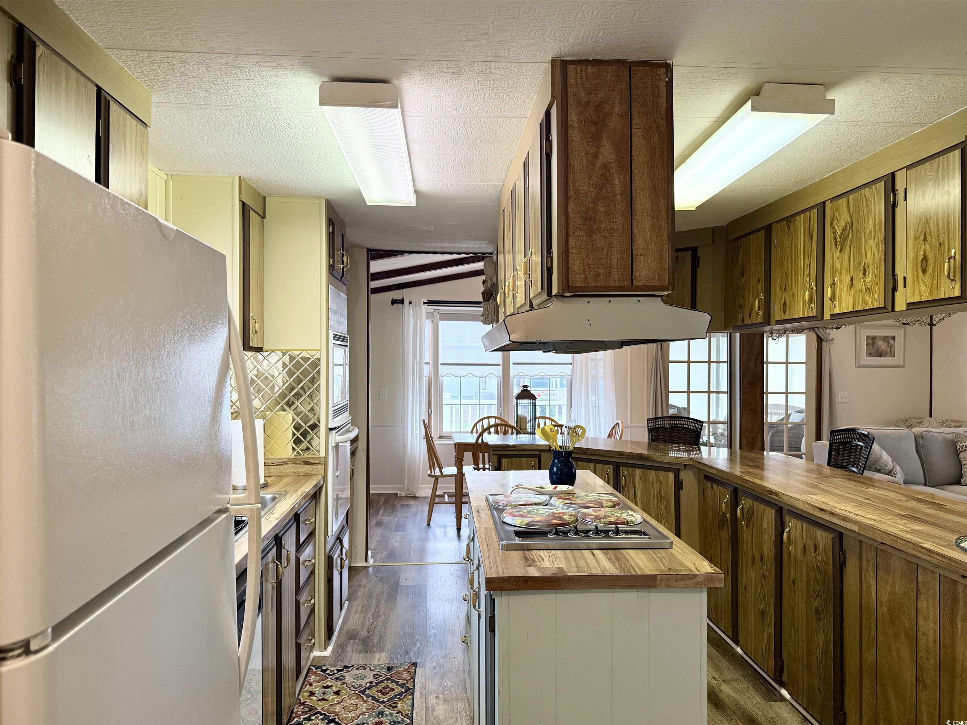 1801 E Lake Surfside Beach, SC 29575 - Photo 2 of 32 Kitchen featuring butcher block countertops, freestanding refrigerator, healthy amount of natural light, dark wood finished floors, and a textured ceiling