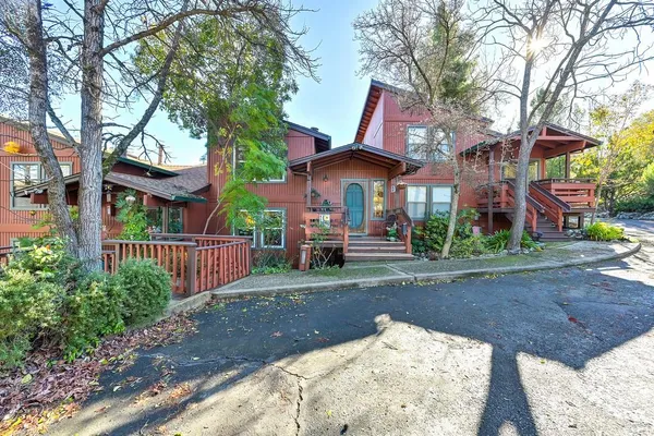 a view of a brick house with large trees and couches next to a yard