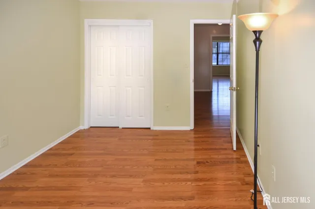 a view of an empty room with wooden floor and a bathroom