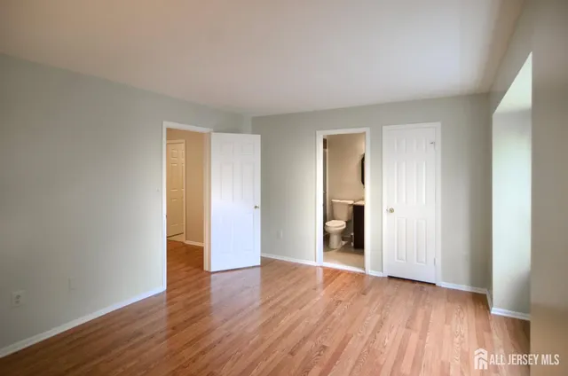 a view of an empty room with wooden floor and closet