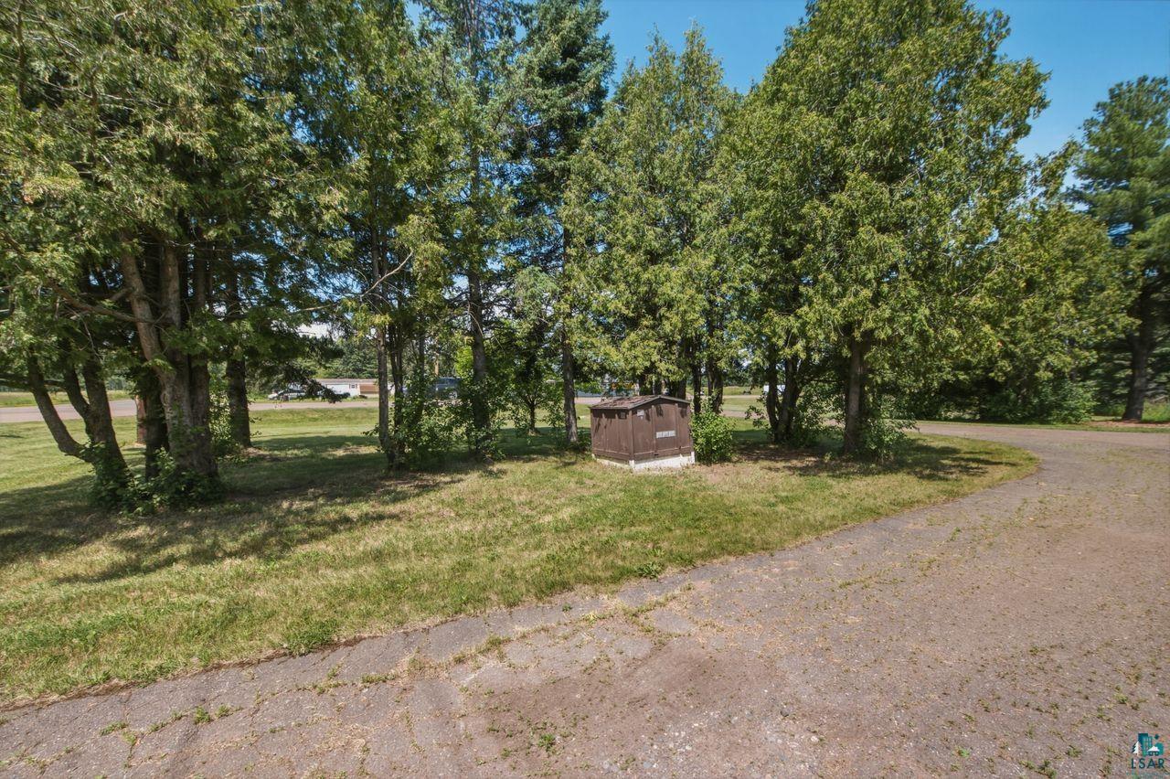 61018 Dahlstrom Road Ashland, WI 54806 - Photo 20 of 28 Gravel driveway with mature trees, green lawn, and a brown utility structure on a concrete pad