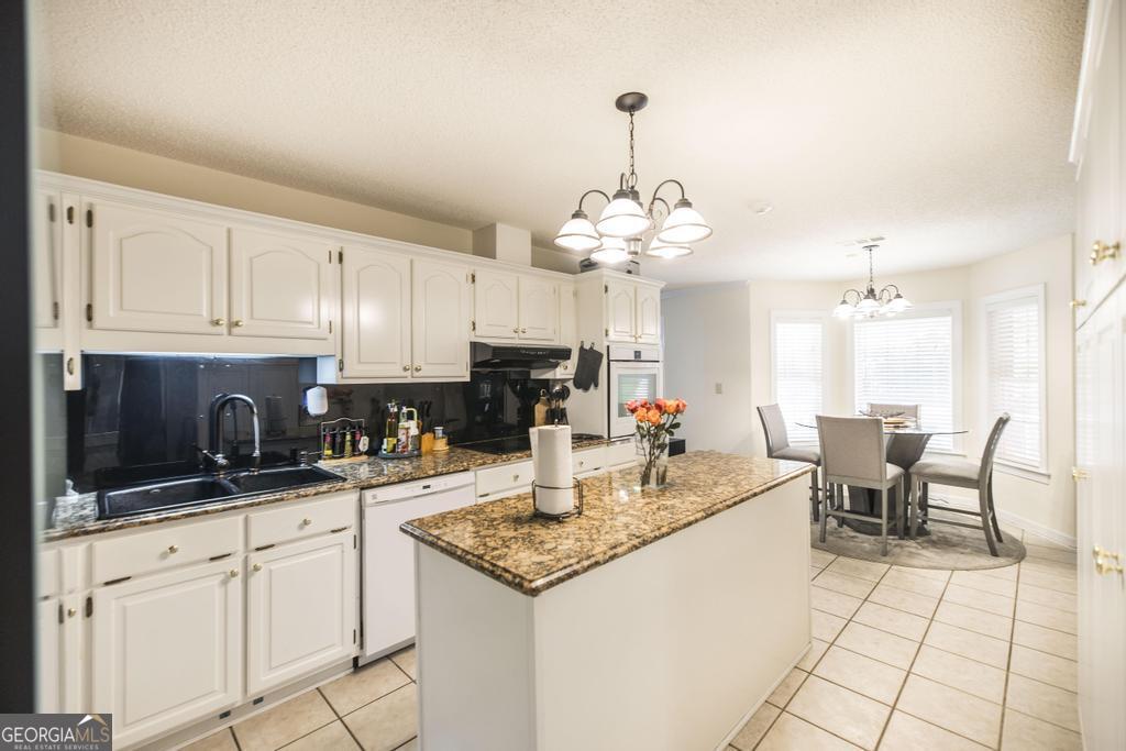 201 Strawberry Circle Dublin, GA 31021 - Photo 25 of 40 a kitchen with granite countertop kitchen island stainless steel appliances a sink stove and cabinets