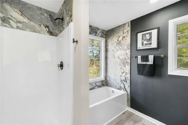 a bathroom with a bathtub a window and a shower