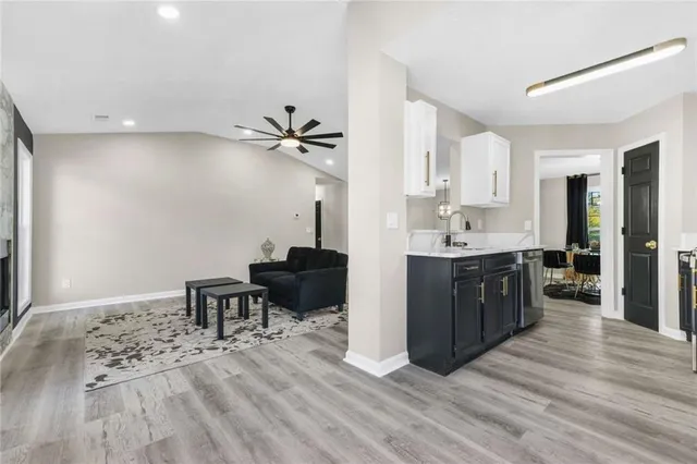 a living room with stainless steel appliances kitchen island granite countertop furniture a sink a refrigerator and wooden floor