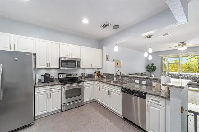 a kitchen with stainless steel appliances granite countertop a stove a sink dishwasher a refrigerator and a microwave