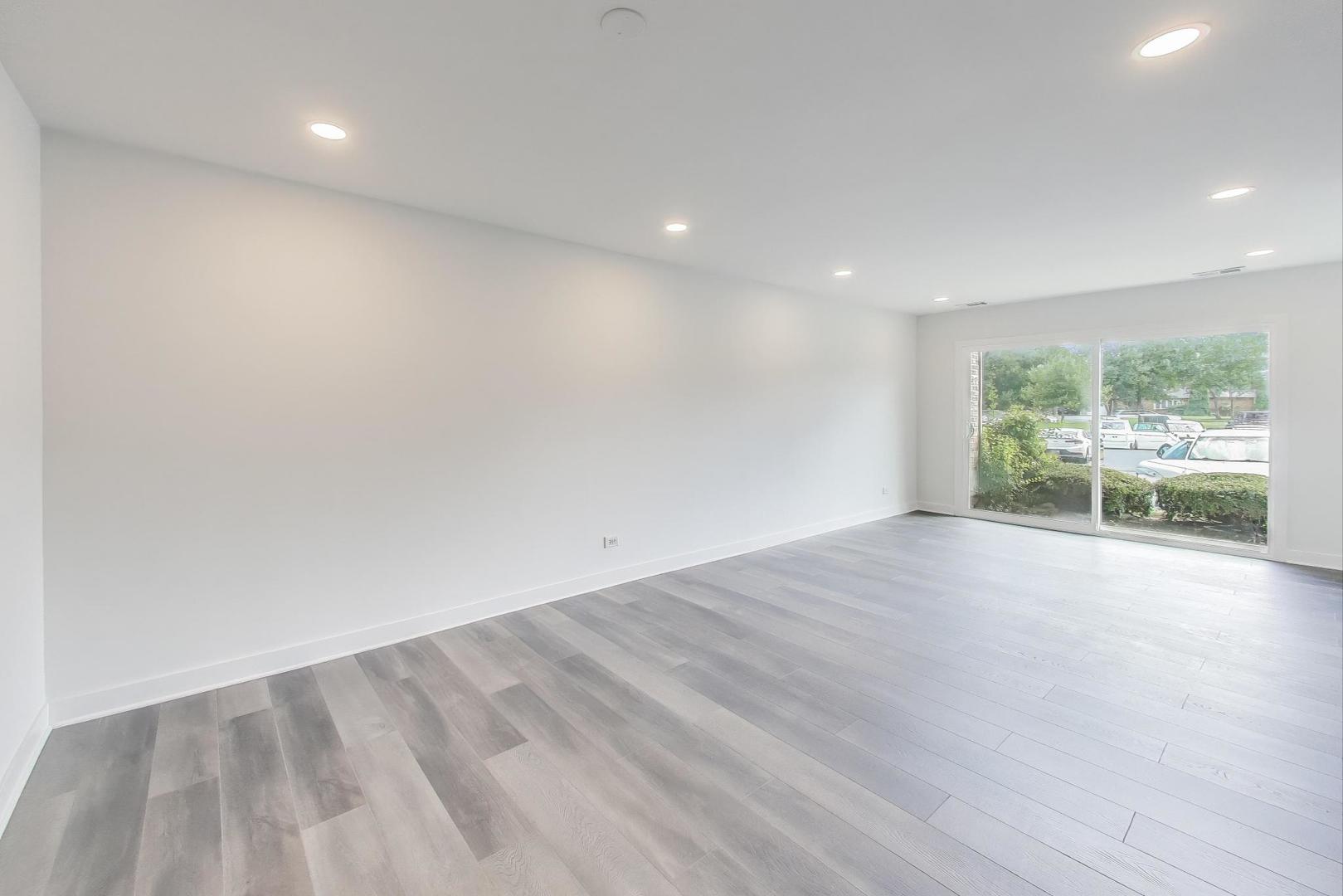 1400 North Elmhurst Road, Unit 106 Mount Prospect, IL 60056 - Photo 2 of 15 an empty room with wooden floor and windows