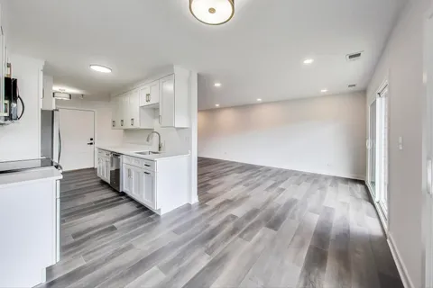 a large kitchen with a lot of counter space and wooden floor