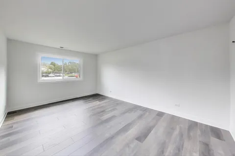 an empty room with wooden floor and window