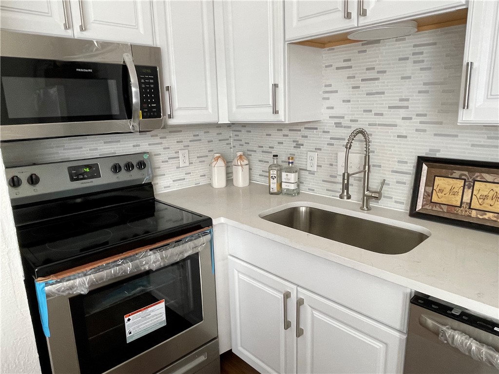 a kitchen with granite countertop white cabinets stove and sink