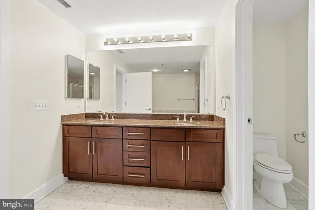 a bathroom with a granite countertop sink a toilet and a mirror