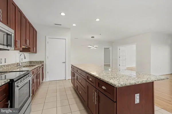 a kitchen with granite countertop kitchen island stainless steel appliances a sink stove and cabinets