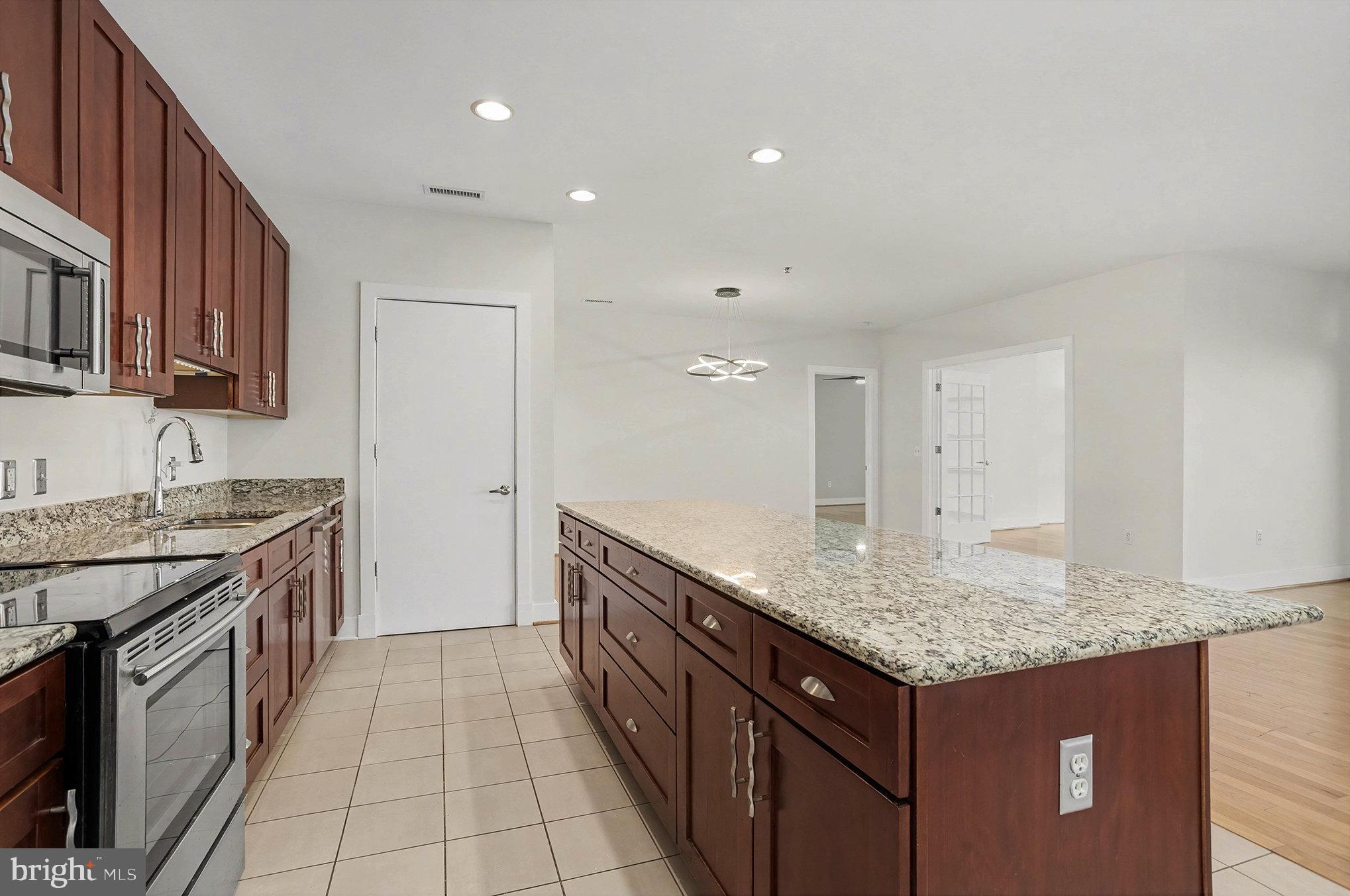 2772 Lighthouse Point East, Unit 201 Baltimore, MD 21224 - Photo 4 of 36 a kitchen with granite countertop kitchen island stainless steel appliances a sink stove and cabinets
