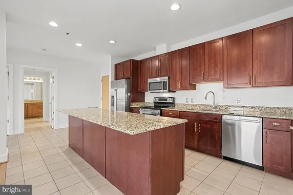 a kitchen with stainless steel appliances granite countertop a sink counter space cabinets and a view of living room