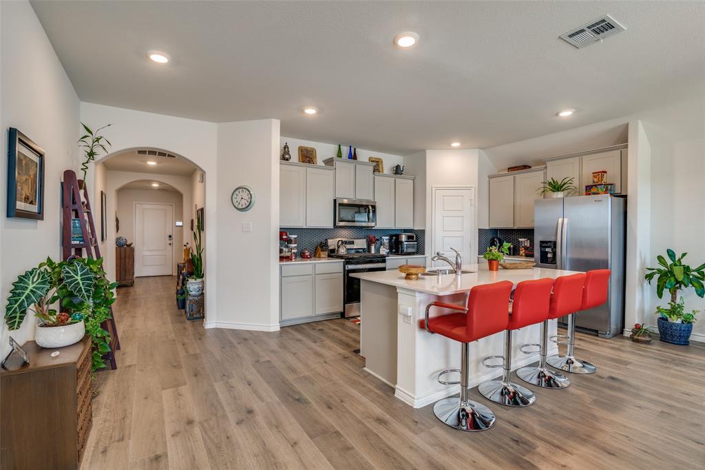 a kitchen with stainless steel appliances kitchen island granite countertop a refrigerator a stove a sink dishwasher and a dining table with wooden floor