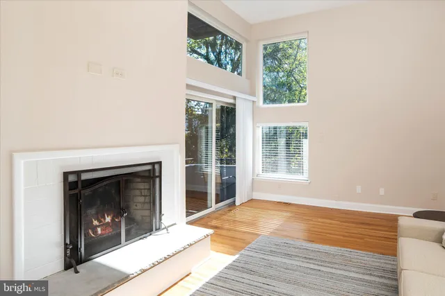 a view of an empty room with wooden floor fireplace and a window