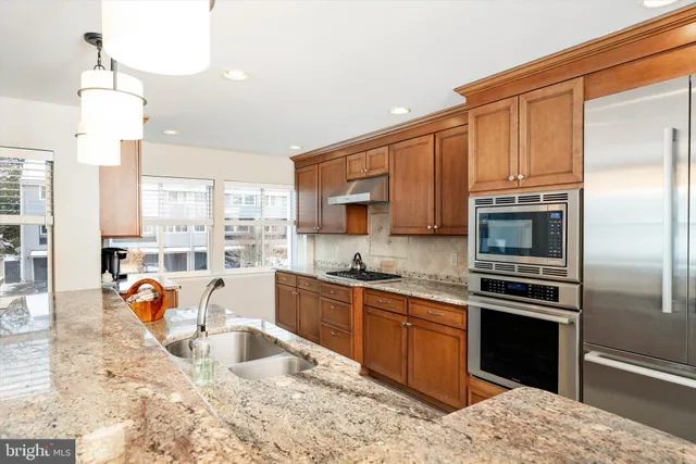 a kitchen with stainless steel appliances granite countertop a stove refrigerator and cabinets