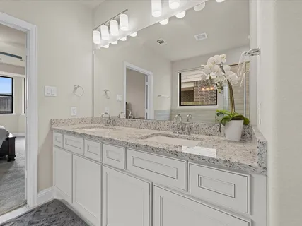 a bathroom with a granite countertop double vanity sink and mirror