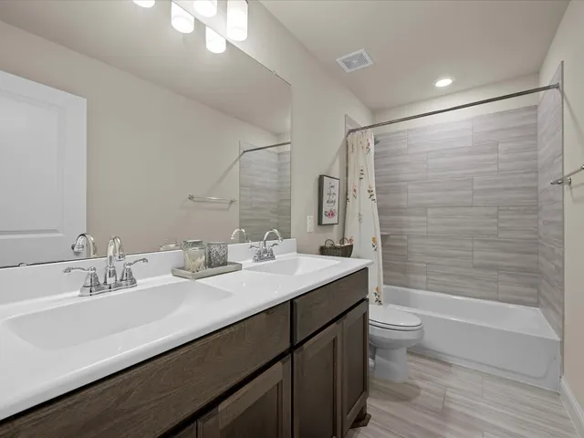 a bathroom with a double vanity sink toilet mirror and bathtub