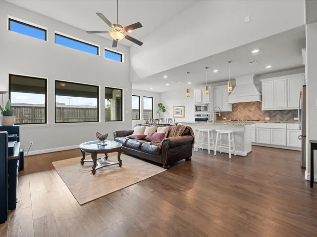 a living room with furniture kitchen view and a wooden floor