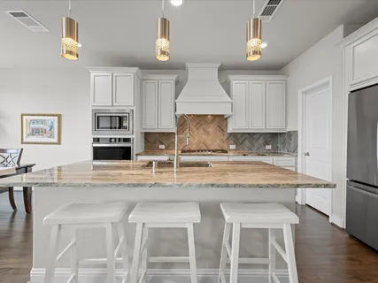 a kitchen with kitchen island granite countertop a stove a sink and a refrigerator