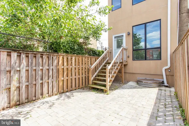 a view of kitchen with kitchen island a refrigerator a stove top oven and a sink with wooden floor