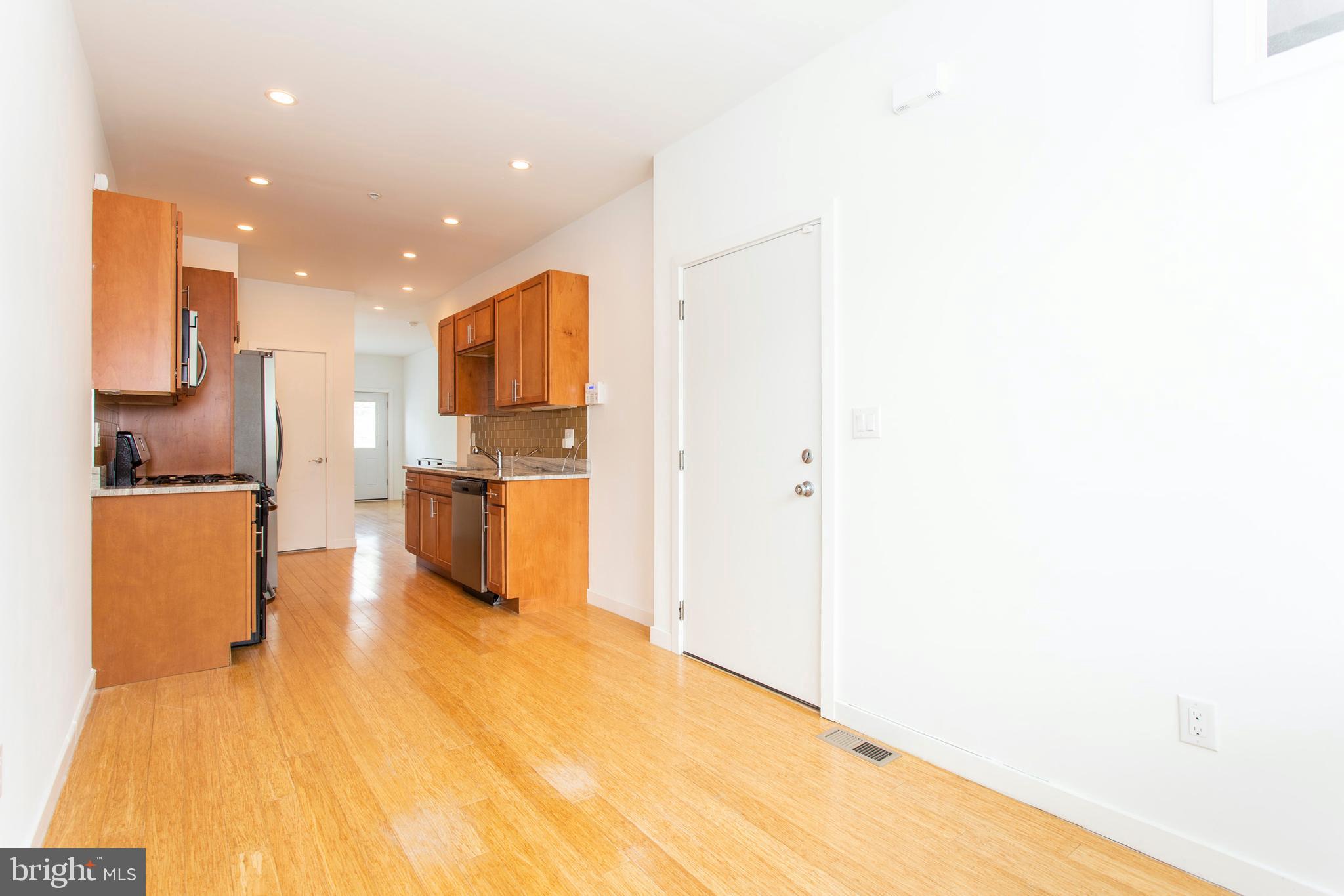 1519 Ogden Street, Unit 1 Philadelphia, PA 19130 - Photo 6 of 19 a view of kitchen with kitchen island a refrigerator a stove top oven and a sink with wooden floor